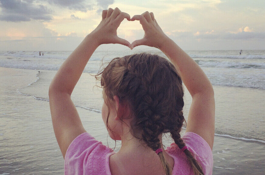 Image of a young girl making a heart shape with her fingers