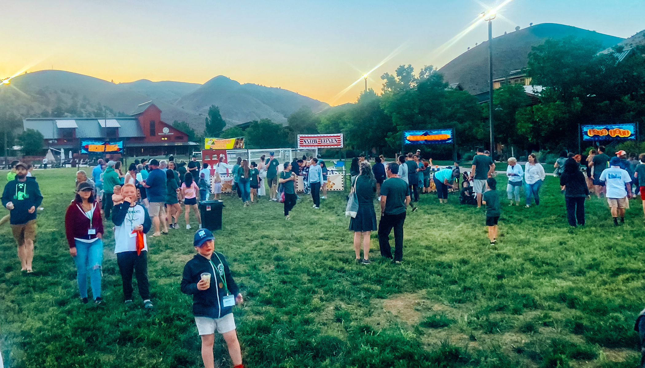 A crowd of people in a grass field at flok Family Camp West in 2023.